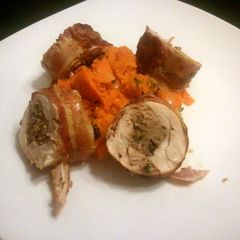 A picture of Bacon wrapped sausage stuffed chicken with sweet potatoes.