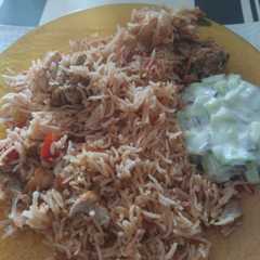 A picture of Chicken Biryani with Cucumber Salad.
