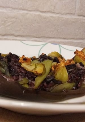 Una foto de Berenjena asada rellena de arroz negro y verduras