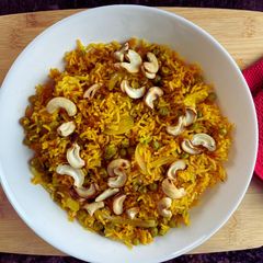 A picture of Tomato Rice with Peas and cashews.
