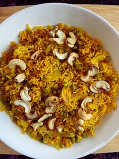 A picture of Tomato Rice with Peas and cashews.