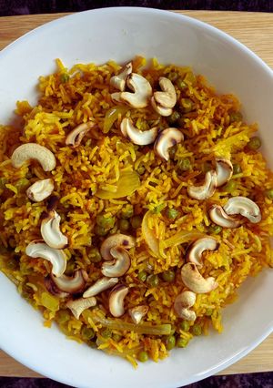 A picture of Tomato Rice with Peas and cashews.