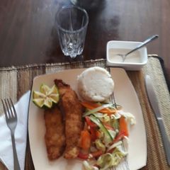 A picture of Coconut crumbed tilapia with a mixed salad and ugali.