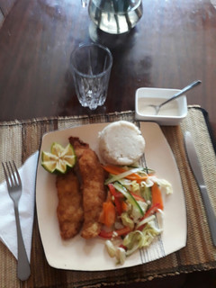 A picture of Coconut crumbed tilapia with a mixed salad and ugali.
