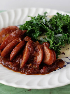 A picture of Spotted Trotter Chicken Currywurst Stewed in a Madras Curry Sauce with Russet Potatoes and Kale.