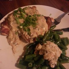 A picture of Bacon wrapped chicken w/Roma tomatoes, mushrooms, green onions in alfredo sauce.