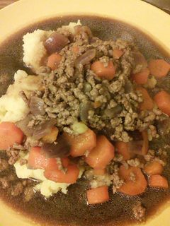 A picture of Minced beef & onion with mash & gravy.