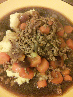A picture of Minced beef & onion with mash & gravy.
