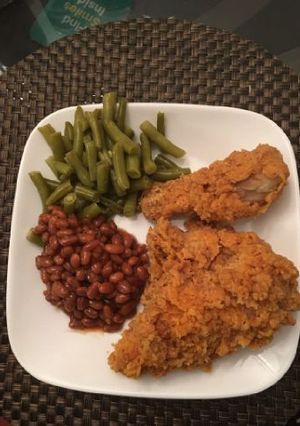 A picture of Chicken with green peas and baked beans.