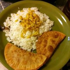 A picture of White rice, sauteed corn and ground turkey empanadas.