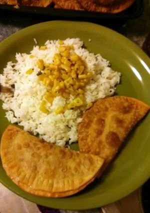 A picture of White rice, sauteed corn and ground turkey empanadas.