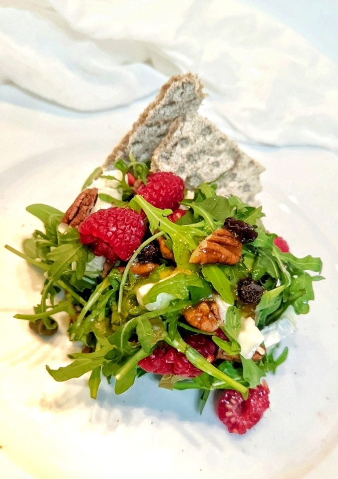 Una foto de Ensalada fresca de rúcula, queso de cabra y frambuesas