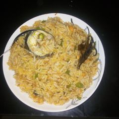A picture of Jollof rice with veggies and fish.