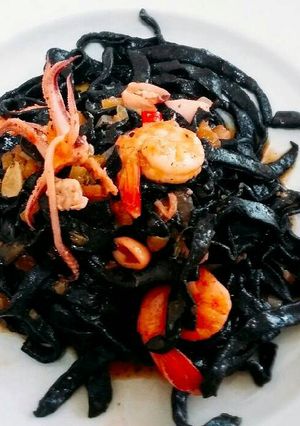 A picture of Homemade fresh squid ink pasta with prawns and squid.
