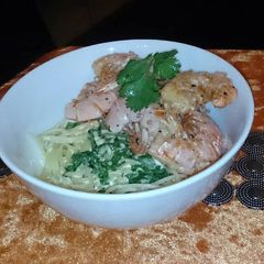 A picture of Sautéed prawns on a bed of creamy spaghetti .