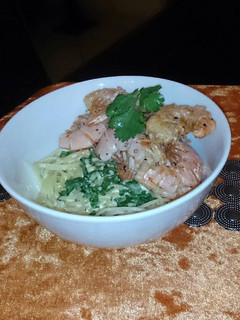 A picture of Sautéed prawns on a bed of creamy spaghetti .