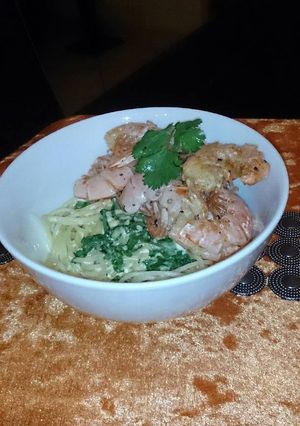 A picture of Sautéed prawns on a bed of creamy spaghetti .