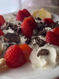 Una foto de Postre de Fresas con nata, rulo de queso dulce y chocolate con sal