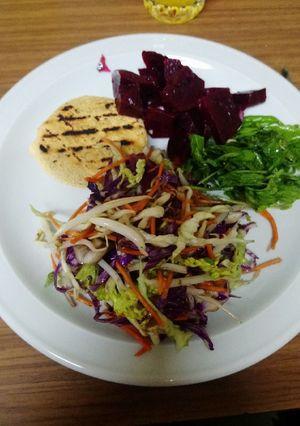 Una foto de Hamburguesa de pescado con rúcula y ensalada variada