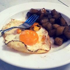 A picture of Spiced potatoes and sunnyside eggs.