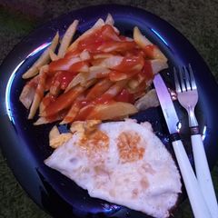 A picture of French fries with fried eggs.