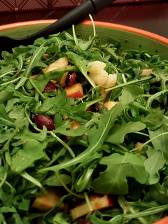 A picture of Arugula salad with candied almonds,walnuts,dates and apple.