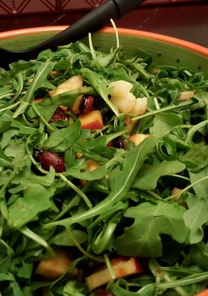 A picture of Arugula salad with candied almonds,walnuts,dates and apple.