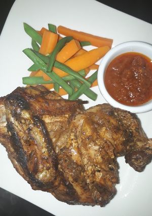 A picture of Grilled chicken with carrots and green peas.