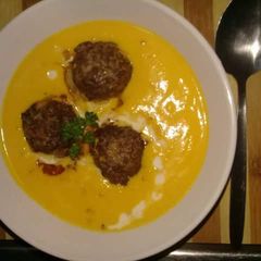 A picture of Creamy pumpkin soup and meatballs.