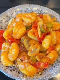 Una foto de Ñoquis con tomate y pepinillos