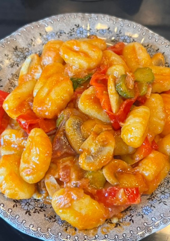 Una foto de Ñoquis con tomate y pepinillos