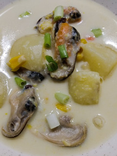 A picture of Seafood chowder with coconut, corn and mussels.
