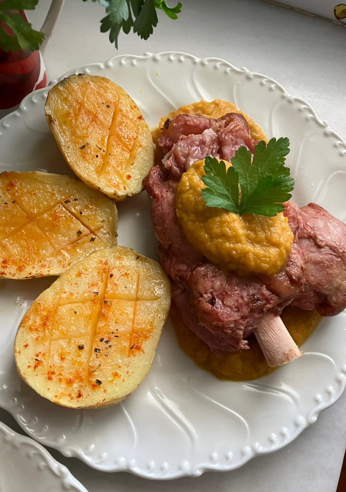 Una foto de Codillo de cerdo con salsa de verduras y patatas asadas