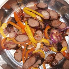 A picture of Sausages with onion and capsicums.