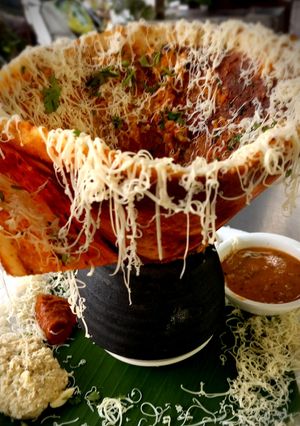 A picture of Cone cheesy Masala Dosa with Coconut Tomato Curry.