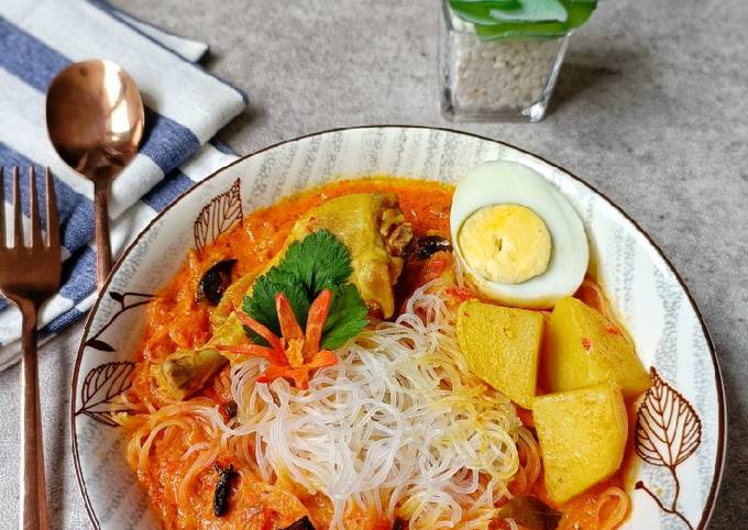 Semangkuk bihun kari pedas dengan kuah kari berempah, dihiasi irisan cabai dan daun bawang segar