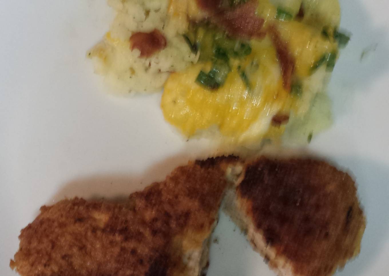 Breaded pork loin chops with a side of mashed potatoes topped with bacon, cheese,green onion