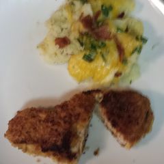 A picture of Breaded pork loin chops with a side of mashed potatoes topped with bacon, cheese,green onion.