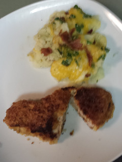 A picture of Breaded pork loin chops with a side of mashed potatoes topped with bacon, cheese,green onion.