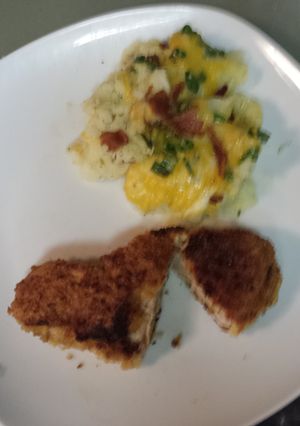 A picture of Breaded pork loin chops with a side of mashed potatoes topped with bacon, cheese,green onion.