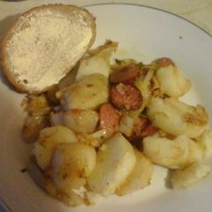 A picture of Cabbage with fried potatoes and smoked sausage.