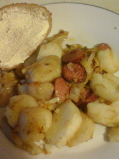 A picture of Cabbage with fried potatoes and smoked sausage.