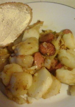 A picture of Cabbage with fried potatoes and smoked sausage.