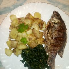 A picture of Onion fried potatoes with fish and greens.