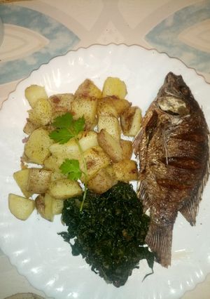 A picture of Onion fried potatoes with fish and greens.