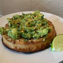A picture of Smashed avocado(gaucamole style) on toasted crumpet.