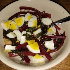 A picture of Sauteed beet greens with hard boiled egg.
