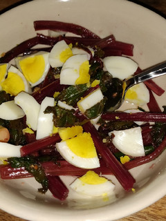 A picture of Sauteed beet greens with hard boiled egg.