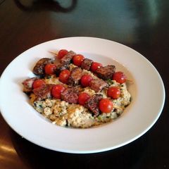 A picture of Grilled lamb and tomato kabobs with mushroom, lemon, amd parmesan couscous.