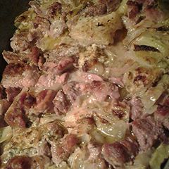 A picture of Cabbage, pork and cauliflower, with a sauce.